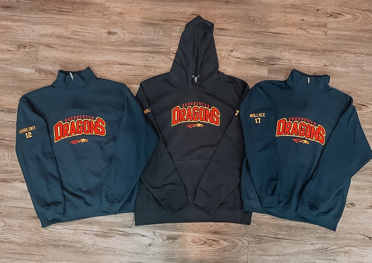 Three hoodies with 'Dorchester Dragons' logo on a wooden surface